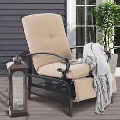 a chair sitting on top of a wooden deck next to a lantern and potted plant