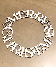 the word merry christmas written in cut out letters on a wooden surface with stars and swirls