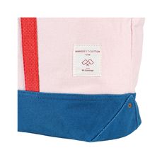 a pink and blue tote bag with a red stripe on the bottom, sitting in front of a white background