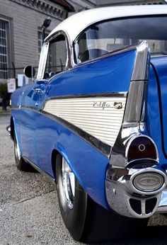 an old blue and white car parked in front of a building