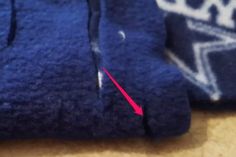 a close up of a blue sweater with a red arrow pointing to the left side