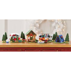 a wooden table topped with lots of toy houses and christmas trees on top of it