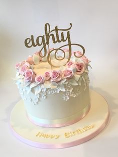 a birthday cake decorated with pink roses and the word eighty on top