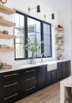 a kitchen with black cabinets and white counter tops, gold pulls on the doors and shelves