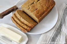 sliced loaf of bread sitting on top of a white plate next to butter and a knife