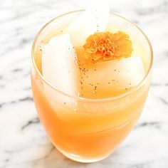 a drink in a glass with ice cubes and an orange flower