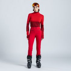 a woman in red ski suit and goggles standing with her back to the camera