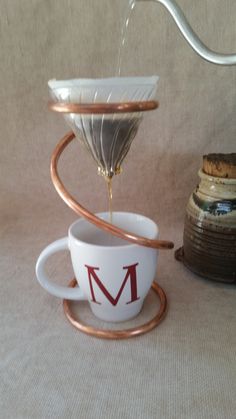 a coffee cup is being filled with liquid from a strainer and saucer on a table