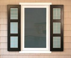 an open window on the side of a house with black shutters and white trim