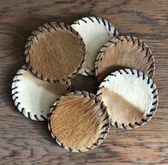 four pieces of cow hide on top of a wooden table with white and brown accents