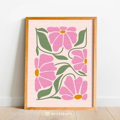 a pink and green floral print in a wooden frame on the floor next to a white wall