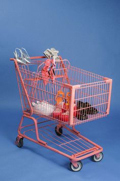 a pink shopping cart filled with items on top of a blue background