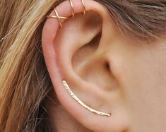 a close up of a person's ear wearing gold earrings