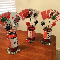 three vases with playing cards in them on a table