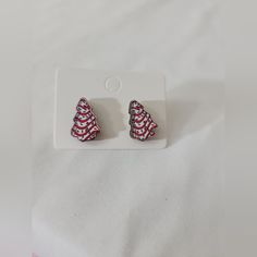 two red and white earrings sitting on top of a white plate