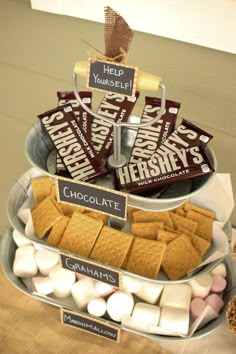 an assortment of candy and marshmallows arranged in a tiered metal tray