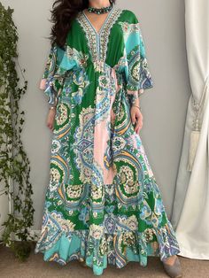 A gorgeous maxi dress that sweeps the floor with its flowy tiered skirt. The elastic waist highlights the figure whilst the loose-fitting V-neck top allows for both comfort and style. The feminine flutter angel sleeves are the perfect finish to the vibrant green and blue paisley pattern. size M, L Colour: Green Material: 100% Viscose Green V-neck Paisley Print Dress, Green V-neck Dress With Paisley Print, Flowy Tiered Bohemian Maxi Dress, Green Billowy Maxi Dress, Bohemian Beach Maxi Dress With Ruffle Hem, Green Bohemian Dress With Ruffle Hem, Bohemian Billowy Maxi Dress, Spring Paisley Print V-neck Maxi Dress, Spring V-neck Maxi Dress With Paisley Print