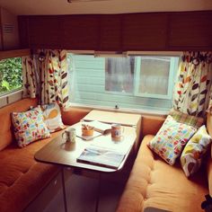 a living area with couches, table and window in the back side of an rv