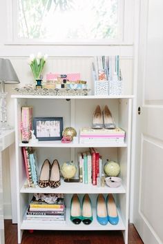 a white shelf filled with lots of books and shoes