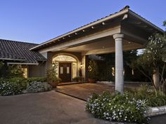 the front entrance to a house at night with lights on and flowers in the foreground