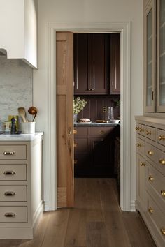 an open door leading to a kitchen with wooden floors