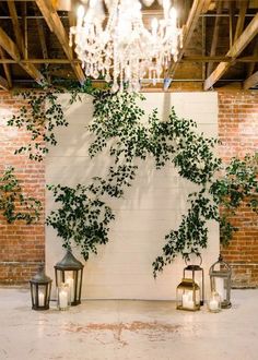 an indoor area with candles and greenery on the wall, chandelier hanging from the ceiling