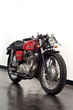 a red and black motorcycle parked in a garage next to a white wall on a wet floor