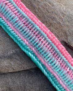 a pink and blue woven object sitting on top of a rock