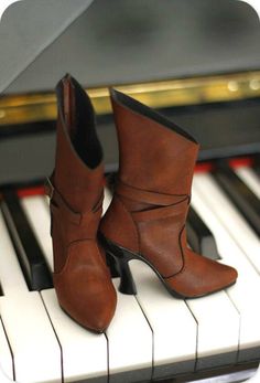 a pair of brown boots sitting on top of a piano