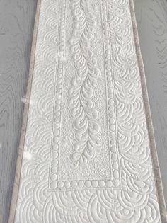 a white quilted table runner sitting on top of a wooden floor