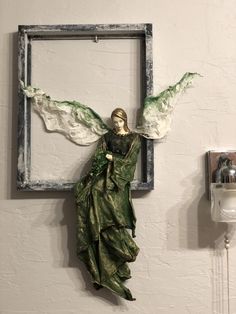 an angel statue hanging on the wall next to a phone charger and light switch