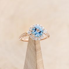 an engagement ring with a blue topaz surrounded by white and brown diamonds on a wooden stand