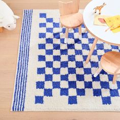 a child's playroom with blue and white checkered rug, wooden chairs and table