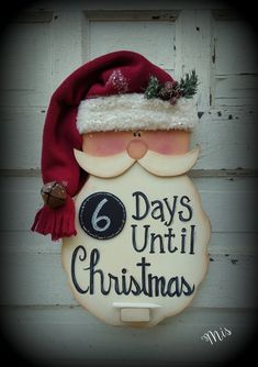 a wooden sign that says 6 days until christmas with a santa hat on it's head