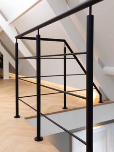 an attic loft with white walls and wood flooring, black iron railings and stairs