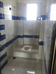 a bathroom with blue and white tiles on the walls, shower stall door and toilet