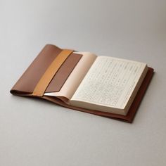 an open book with a leather cover and two pages on the front, sitting on top of a table