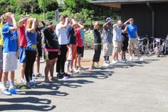 a group of people standing next to each other in front of a building with bicycles