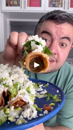 a man holding a plate full of food and eating it with his mouth wide open