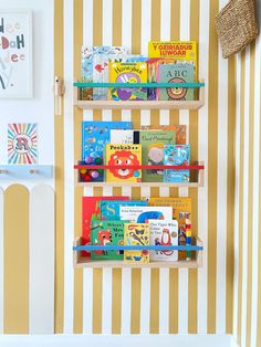 the bookshelf is filled with children's books in front of a striped wall