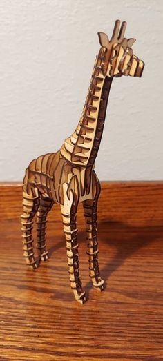 a wooden giraffe standing on top of a wooden table next to a wall