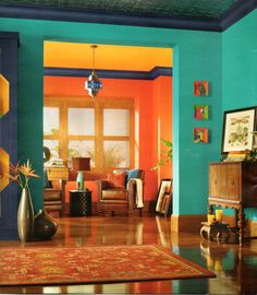 the interior of a living room painted in bright blue, orange and yellow colors with an area rug on the floor