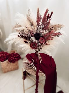 an arrangement of dried flowers and feathers on a chair