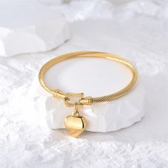 Indulge in timeless elegance with the Lara Heart Bangle. This exquisite bangle features a delicate love lock heart detail, meticulously shaped in the form of a heart. Add a touch of love and sophistication to any outfit with this luxurious piece. Measures: Bracelet, 6cm in diameter. Heart pendant is 17mm tall and 14.2mm wide Love Lock, Gold Plated Bangles, Vintage Inspired Fashion, Heart Shape Pendant, Vintage Heart, Gold Bangles, Shape Design, Exquisite Design, Vintage Accessories