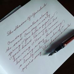 a pen sitting on top of a piece of paper next to a writing sample that is written in cursive ink