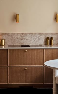 a modern kitchen with wooden cabinets and gold accents on the wall, along with a marble counter top