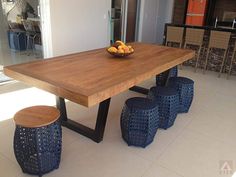 a wooden table with four blue stools and a bowl of oranges on it