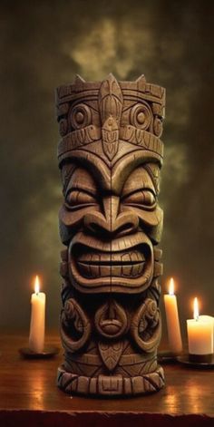 a tiki statue sitting on top of a wooden table next to three lit candles