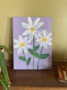 a painting of white daisies on a purple background next to a potted plant