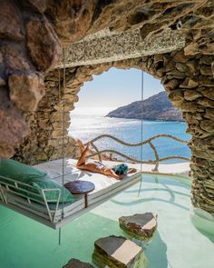 a woman laying on a bed in the middle of a room with water and rocks